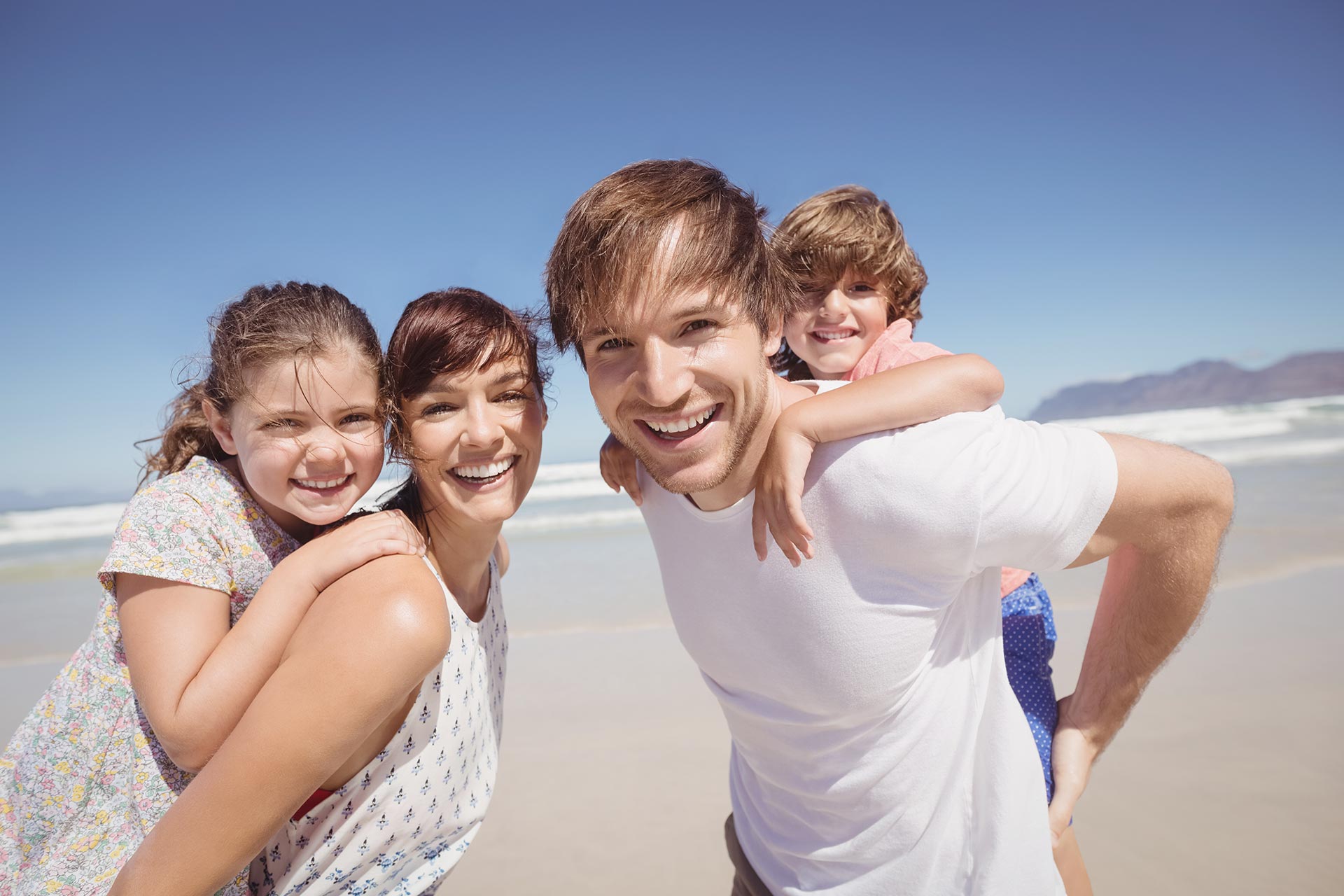 portrait of family smiling together at beach ZHKPVJJ