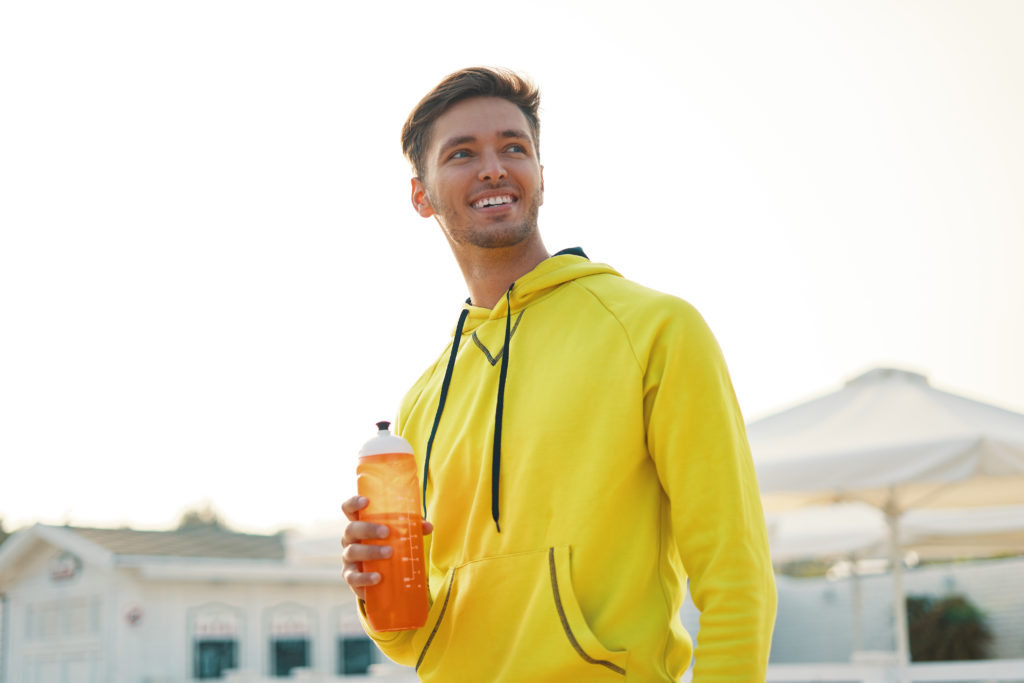 Smiling Healthy Athletic Man With Fit Body Holding Bottle Of Ref